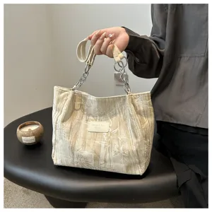 Detailed view of women's beige tote bag, featuring chic metal chain and daily commuter style.