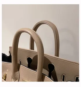 Elegantes taupefarbenes Handtaschen-Griffdetail im klassischen strukturierten Tote-Design.