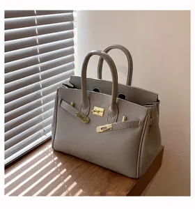 Graue Handtasche Detailaufnahme, hochwertige Ledertextur, edle goldene Beschläge, klassisch.