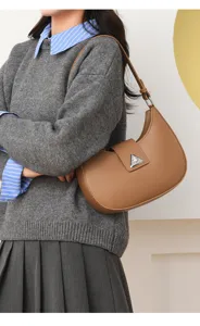 Chic brown leather shoulder bag for women, trendy crescent hobo design with metal triangle clasp.