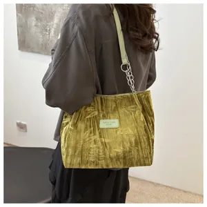 Green velvet shoulder bag detail view, showing soft fabric texture and chain strap design.