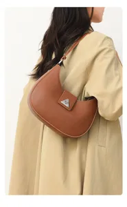 Close-up detail of the brown leather crescent shoulder bag with metal clasp hardware.