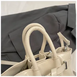 Close-up detail of stylish beige leather handbag handle and metal hardware accessories.