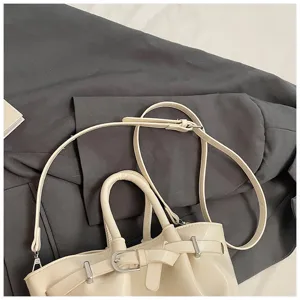 Close-up view of elegant beige bucket bag shoulder strap and metal buckle detail.