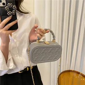 Detail view of grey embossed hard box handbag with chain strap and twisted top handle stylish.