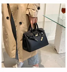 Schwarze Handtasche Detail, elegante Henkeltasche aus Leder mit goldenem Metallverschluss.