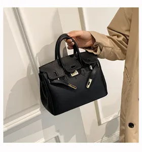 Detailaufnahme einer schwarzen Kunstleder-Handtasche mit Metallverschluss und zwei Henkeln.