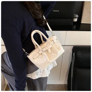 Chic patent leather shoulder handbag detail, elegant cream white color with stylish buckle strap.