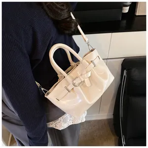 Elegant off-white patent leather handbag with double handles and trendy buckle strap detail.
