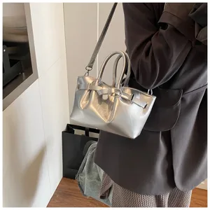 Silver metallic handbag detail showing the stylish buckle strap, dual handles, and premium texture.