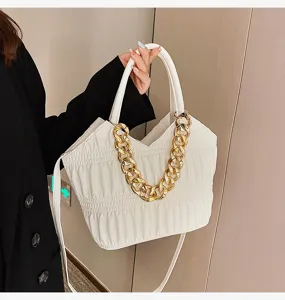 Detail shot of white pleated shoulder handbag featuring a chunky gold chain decoration.