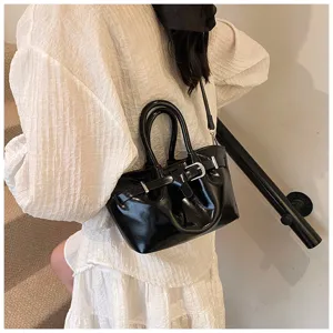 Black patent leather handbag detail, stylish bucket bag with buckle design, ideal crossbody.