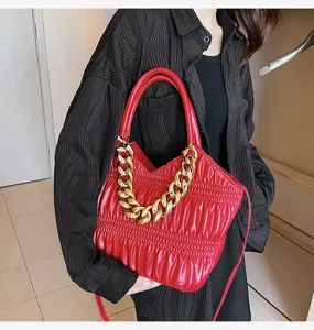 Detail shot of red PU leather shoulder handbag featuring chunky gold chain strap and pleats.