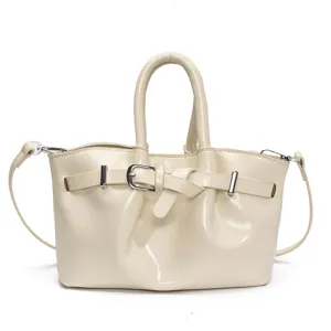 Beige patent leather handbag for women, stylish tote bucket bag with top handle and strap.