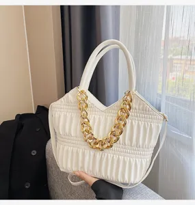 White pleated handbag detail shot showing chic chunky gold chain and soft leather texture.