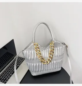 Silver pleated tote handbag detail view featuring chunky gold chain handle and shoulder strap.