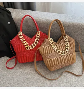 Detailed view of fashionable ruched women shoulder handbag featuring chunky gold chain.
