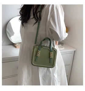 Close-up detail of the stylish green crossbody cookie handbag featuring metallic accent buckles.