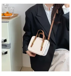 Close-up detail of stylish niche biscuit handbag with brown handles and chic metal buckle.