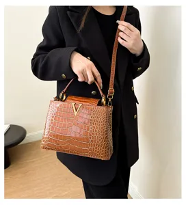 Crocodile pattern top handle shoulder bag detail showcasing luxury metal V hardware design.
