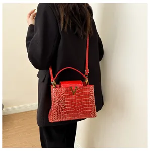 Detailed view of the luxury red crocodile pattern handbag featuring a sleek metallic V logo closure.