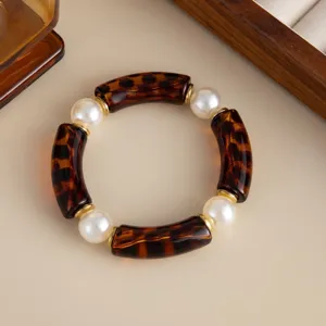 Close-up of a tortoiseshell-patterned curved tube bracelet with white faux pearls