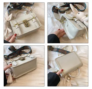 Vintage schoudertas voor dames met slot, brede riem en schattige konijnenhanger.