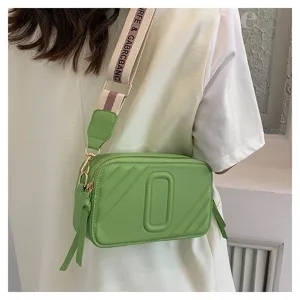 Détail de sac bandoulière vert avec large sangle tendance, double fermeture et matelassage.