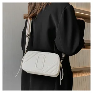 Gros plan sur le sac bandoulière appareil photo matelassé blanc élégant avec large sangle chic.