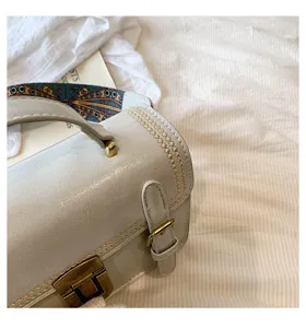Retro slot handtas detail, premium lichtgrijze textuur, elegant metalen beslag en etnische band.