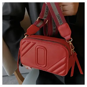 Sac bandoulière rouge en cuir pour femme, sac appareil photo tendance avec sangle large chic.