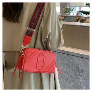 Élégant sac bandoulière rouge pour femme avec large sangle, sac appareil photo tendance.