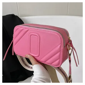 Sac bandoulière rose pour femme, sac appareil photo tendance avec sangle large et élégante.