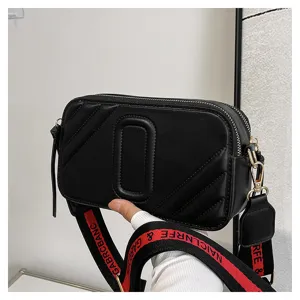 Sac à bandoulière matelassé noir pour femme avec sangle large et détails dorés chics.
