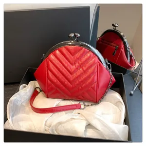 Close-up detail of the red quilted shell bag, showing exquisite stitching and metal kiss lock.
