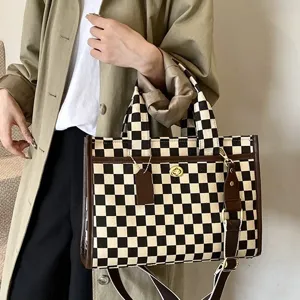 Κομψή τσάντα tote από καμβά σε μαύρο και λευκό καρό με καφέ φινίρισμα και λουρί ώμου.