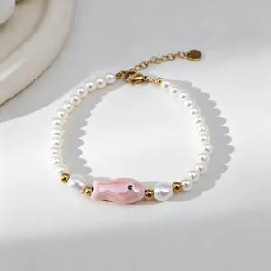 Vue détaillée d'un bracelet en perles de style bohème avec un petit poisson rose en céramique.