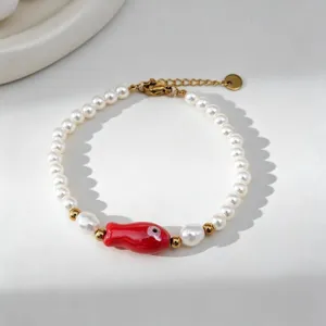 Gros plan sur un bracelet en perles fait main avec un charme de poisson rouge.