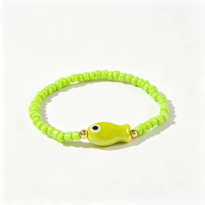 Zoom sur un bracelet en perles vertes de style bohème avec un charmant petit poisson.