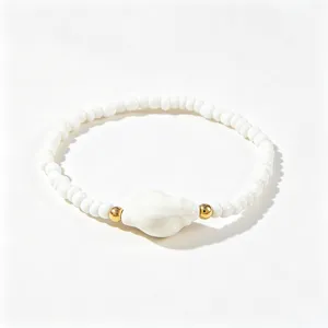 Gros plan sur un bracelet de perles blanches de style bohème avec un accent de coquillage