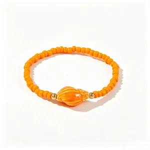 Macro d'un bracelet bohème montrant des perles orange vif et un pendentif de coquillage