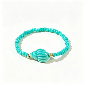 Détail d'un bracelet de perles turquoise de style bohème avec un pendentif en coquillage.