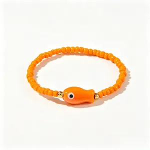 Vue détaillée d'un bracelet en perles orange avec un charm poisson et des perles dorées