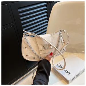 Detailed view of white crocodile pattern shoulder underarm bag with metal heart buckle and chain.