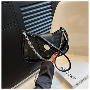 Close-up detail of black crocodile pattern shoulder bag with metal chain and heart buckle.