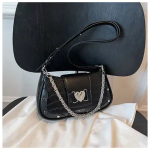 Black stone grain underarm bag detail, featuring metal heart clasp and chunky chain strap.