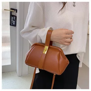 Bruine lederen kiss-lock handtas detail opname, stijlvolle schouder crossbody tas textuur.