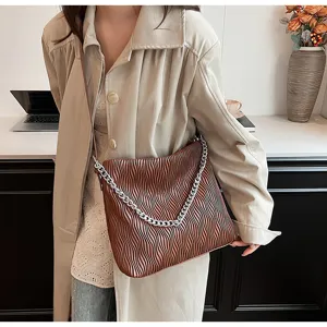 Detail shot of the brown pleated shoulder bag showing premium texture and silver chain strap.
