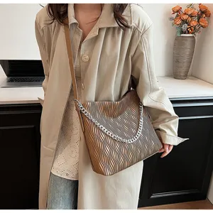 Close-up detail shot of stylish pleated shoulder bag with metal chain strap and large capacity.