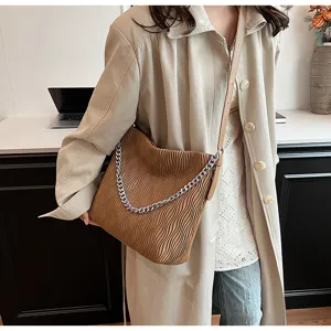 Close-up detail of stylish brown pleated shoulder bag with chic silver chain strap for women.
